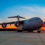 A C-17 sits on the tarmac at sunset
