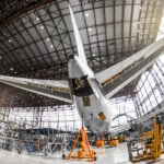 Large passenger aircraft on service in an aviation hangar rear view of the tail, on the auxiliary power unitand tail altitude control, elevating rudder