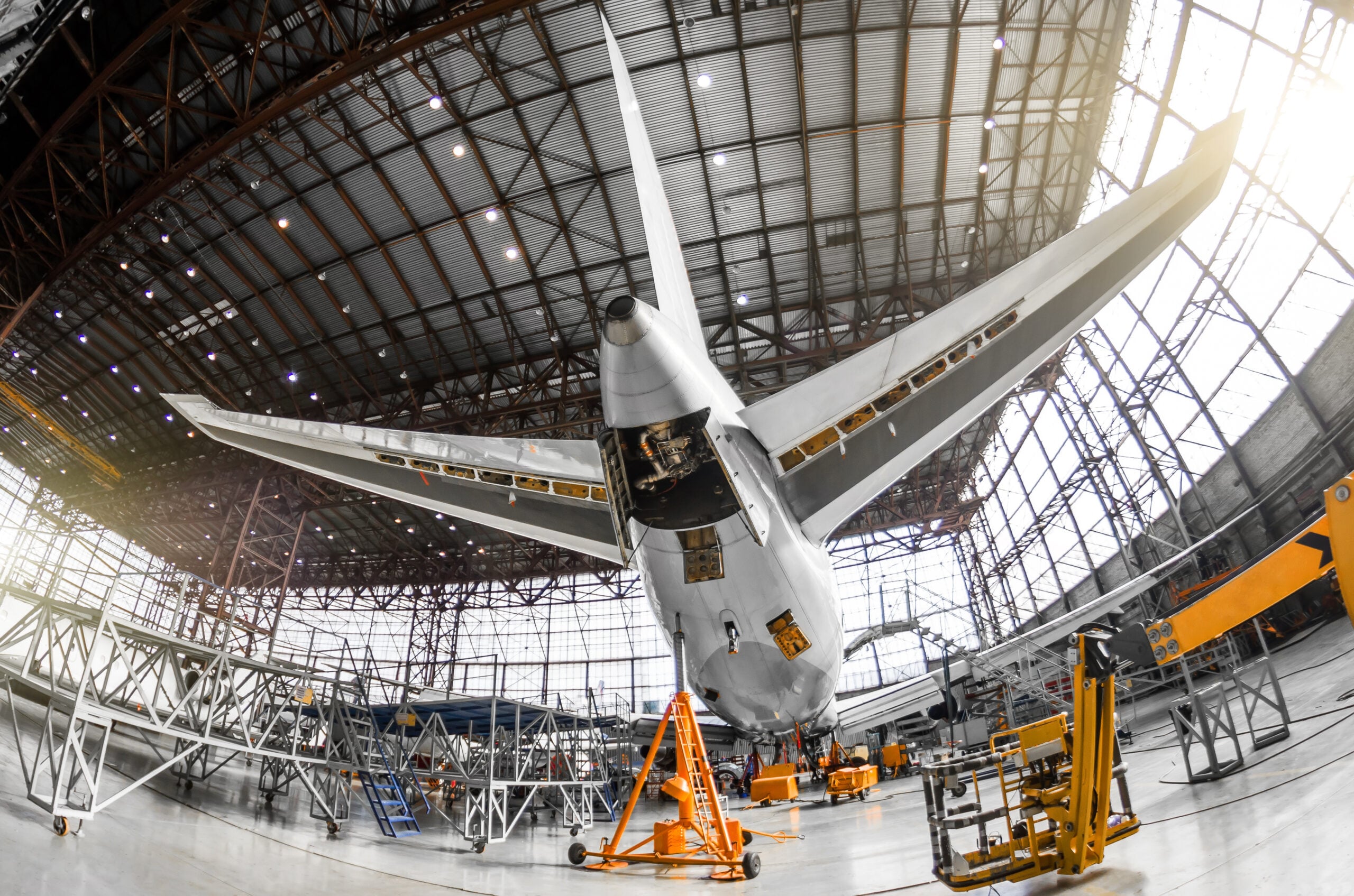 Large passenger aircraft on service in an aviation hangar rear view of the tail, on the auxiliary power unitand tail altitude control, elevating rudder