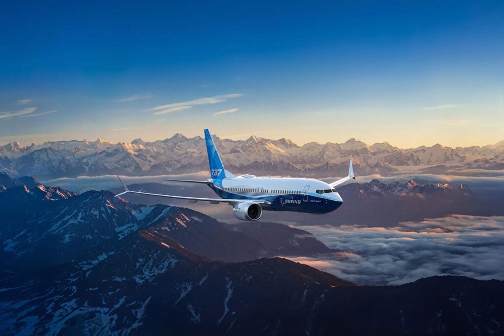 Boeing 737-7 airplane flying over snowy mountain background